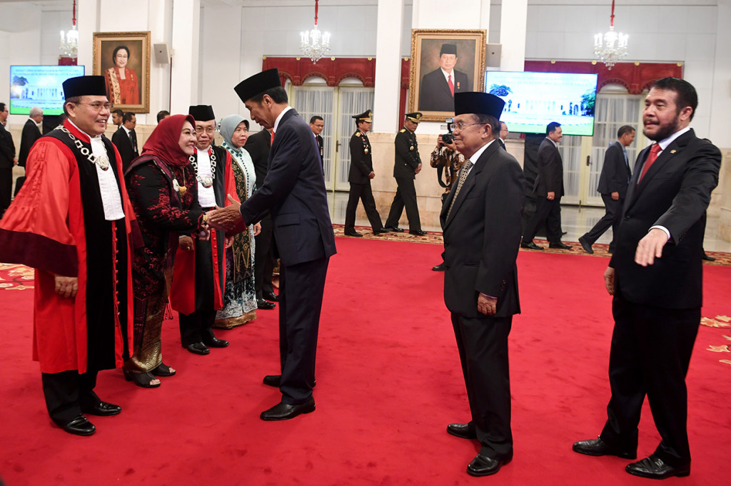 Presiden Joko Widodo (ketiga kanan) bersama Wapres Jusuf Kalla (kedua kanan) dan Ketua Mahkamah Konstitusi Anwar Usman memberikan ucapan selamat kapada Hakim Konstitusi Aswanto (kiri) dan Wahiduddin Adams seusai mengucapkan sumpah di Istana Negara, Jakarta.