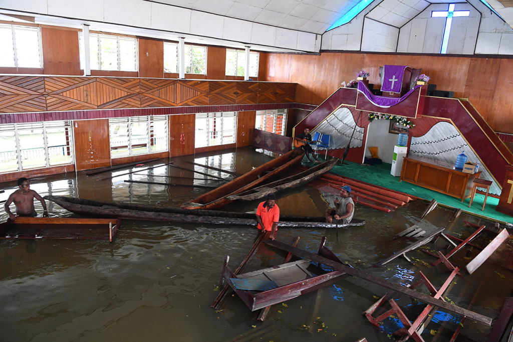 Warga merapikan kursi gereja yang terendam banjir akibat meluapnya Danau Sentani dampak dari banjir bandang Sentani di Kampung Yoboi, Danau Sentani, Sentani. Antara Foto/Zabur Karuru