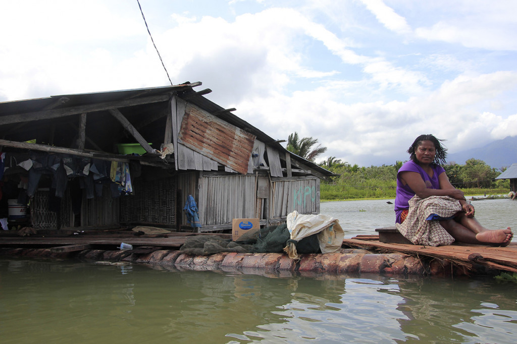 Seorang warga duduk di halaman rumahnya yang terendam banjir akibat meluapnya Danau Sentani dampak dari banjir bandang Sentani di Kampung Yoboi, Danau Sentani. Antara Foto/Gusti Tanati