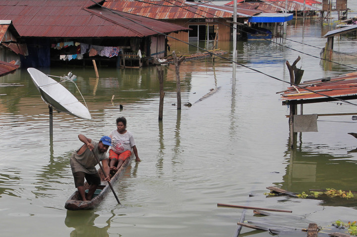 Warga menggunakan perahu melintas di antara rumah yang terendam banjir akibat meluapnya Danau Sentani dampak dari banjir badang Sentani di Kampung Yoboi, Sentani. Antara Foto/Gusti Tanati