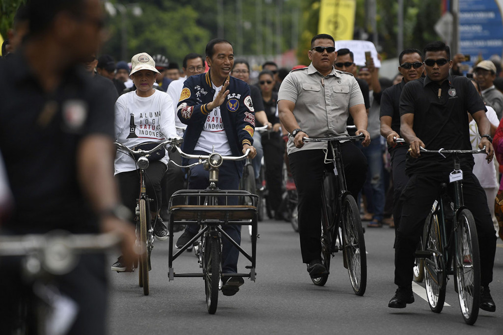 Sambil mengayuh sepeda, sepanjang perjalanan Joko Widodo melempar senyum ramah dan melambaikan tangan kepada masyarakat yang berjajar di pinggir jalan. Masyarakat pun serentak berteriak memanggil Jokowi.
