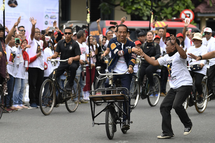 Calon Presiden petahana Joko Widodo  menyapa pendukungnya saat bersepeda onthel menuju lokasi Deklarasi Alumni Jogja Satukan Indonesia di Stadion Kridosono, Yogyakarta.