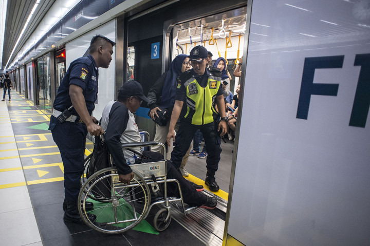 Petugas membantu seorang penyandang disabilitas naik ke kereta MRT di Stasiun MRT Bundaran HI, Jakarta.