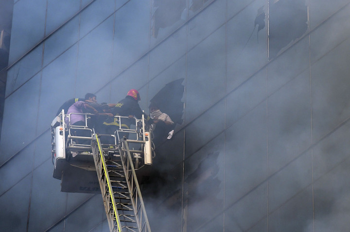 Petugas berupaya mengevakuasi para korban kebakaran yang terjebak di dalam gedung dengan memecahkan kaca.