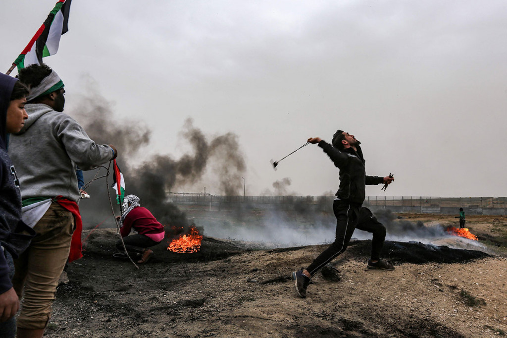 Warga Palestina membalas tembakan peluru dan gas airmata tentara Israel dengan lemparan batu.