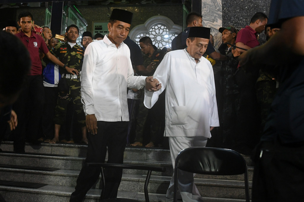 Calon Presiden petahana nomor urut 01 Joko Widodo (kiri) bergandengan tangan dengan Habib Luthfi (kanan) usai menjalankan Salat Magrib berjamaah di Masjid Agung Brebes, Jawa Tengah.