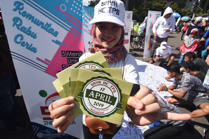 Warga menunjukkan stiker ajakan menggunakan hak pilih pada kegiatan sosialisasi Pemilu di Bundaran HI, Jakarta.