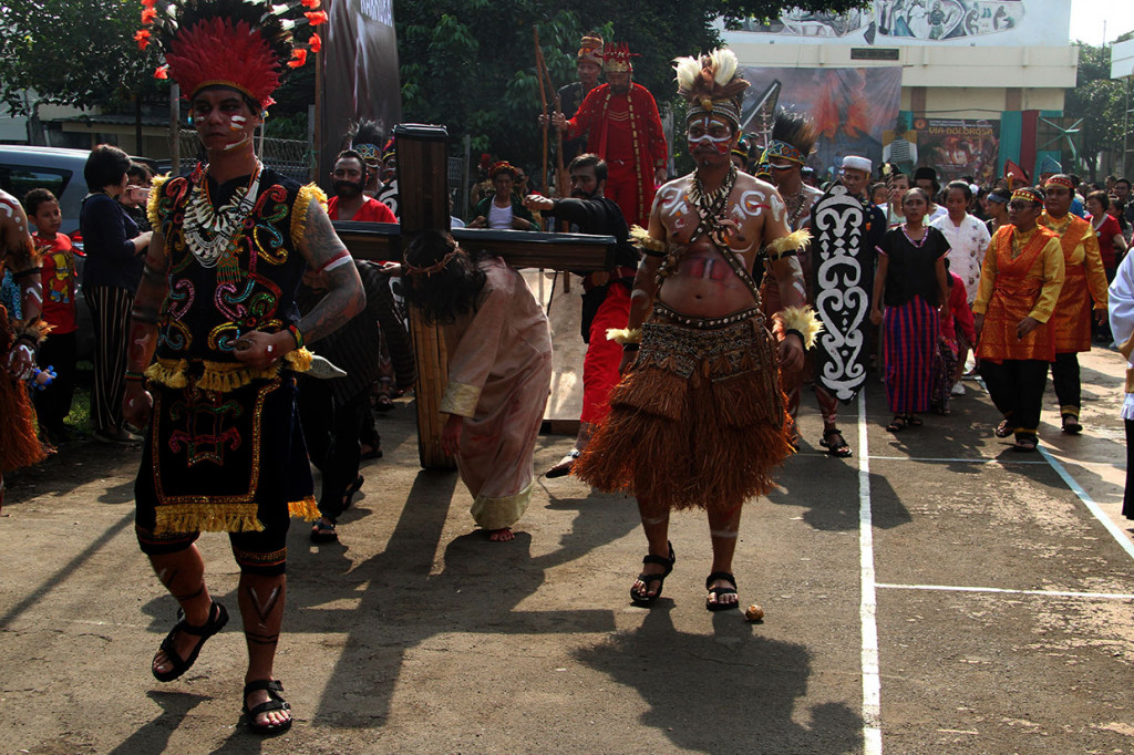 Umat Katolik mengenakan pakaian adat saat mengikuti prosesi drama jalan salib atau Tablo Inkulturasi di Gereja Santo Fransiskus Asisi Paroki, Jakarta.