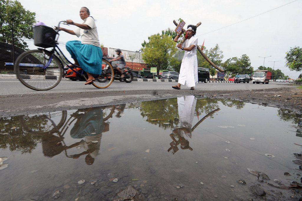 Seorang umat Katolik Iwan Purwoko memikul salib bertuliskan 'NKRI' saat melakukan jalan salib dari Tugu Batas Kota Prambanan menuju Gunungan Batas Kota Tegalgondo di Jalan Jogja-Solo, Klaten, Jawa Tengah, Jumat, 19 April 2019.