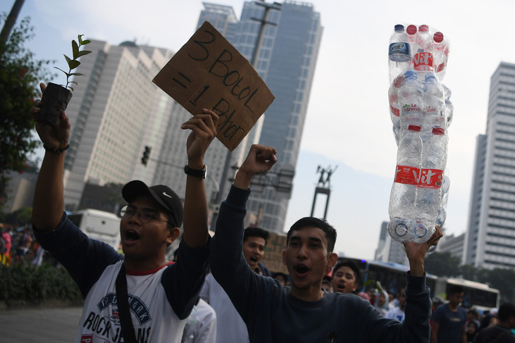 Mahasiswa Universitas Indonesia membawa poster, bibit pohon dan botol minuman plastik ketika melakukan aksi di kasawan Bundaran HI Jakarta.