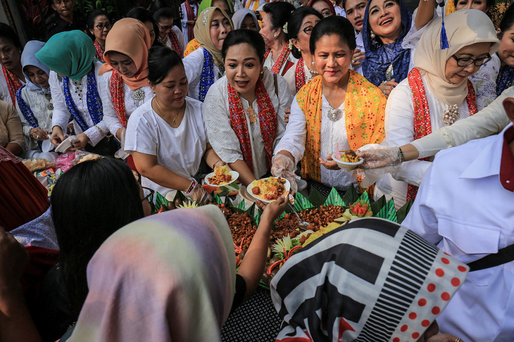 Ibu Negara Iriana Joko Widodo (kedua kanan) beserta pengurus Himpunan Ratna Busana (HRB) membagikan nasi tumpeng kepada warga saat menghadiri acara peringatan Sewindu HRB di Batik Danar Hadi, Solo, Jawa Tengah.
