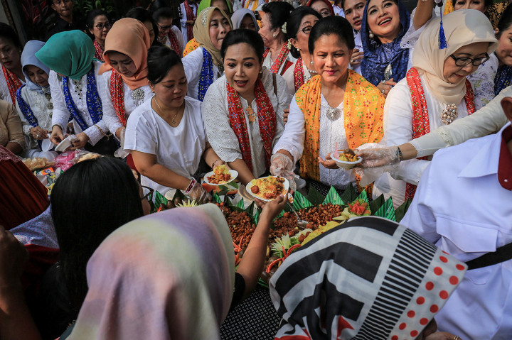 Ibu Negara Iriana Joko Widodo (kedua kanan) beserta pengurus Himpunan Ratna Busana (HRB) membagikan nasi tumpeng kepada warga saat menghadiri acara peringatan Sewindu HRB di Batik Danar Hadi, Solo, Jawa Tengah.