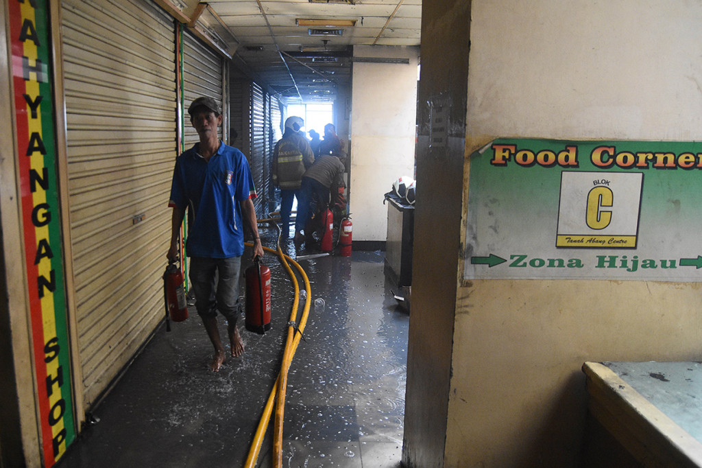 Pedagang membawa alat pemadam api ringan (apar) usai melakukan pembasahan pada kebakaran yang terjadi di Gudang baju blok C Pasar Tanah Abang, Jakarta.