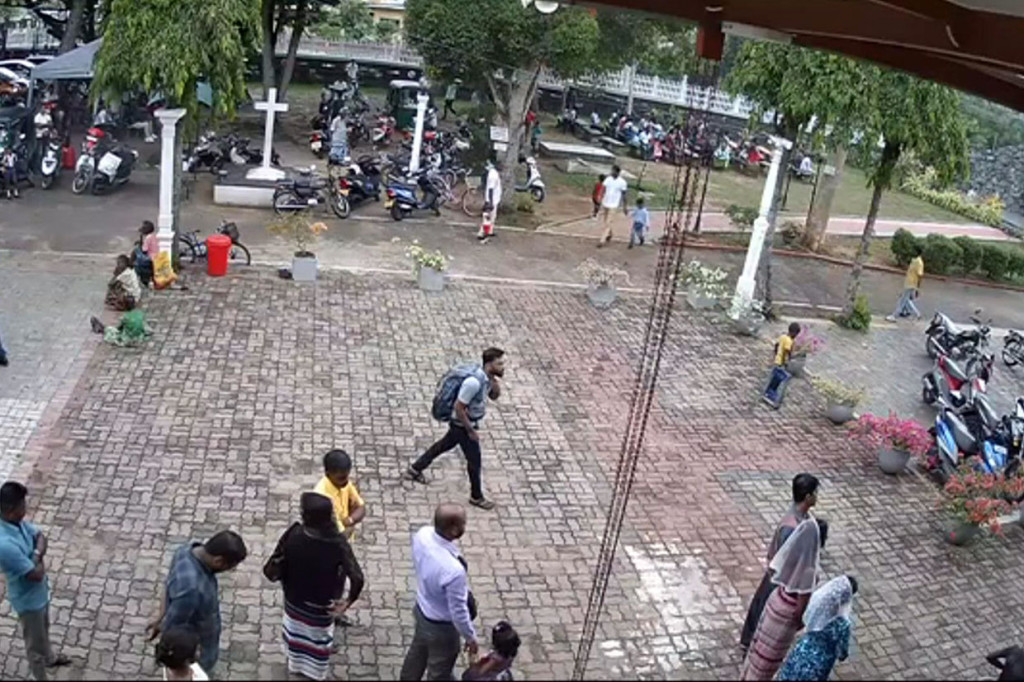 Pria (tengah) yang membawa tas ransel besar berjalan memasuki gereja melewati sejumlah jemaat sebelum terjadinya ledakan.