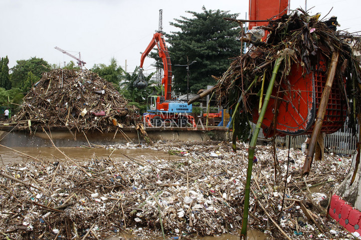 Petugas kebersihan dibantu alat berat mengeruk dan membersihkan sampah yang menumpuk di Pintu Air Manggarai, Jakarta, Rabu, 24 April 2019.