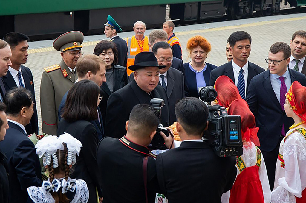 Kim mengenakan jas hitam dan fedora disambut para pejabat Rusia di stasiun kereta api Rusia yang terletak di perbatasan Korut. Afp Photo/Alexander Safronov