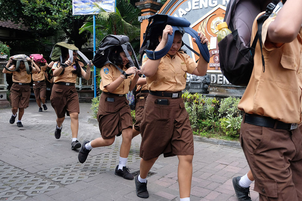 Siswa SMPN 3 Denpasar menyelamatkan diri dengan melindungi kepala menggunakan tas saat terjadi gempa dalam simulasi memperingati Hari Kesiapsiagaan Bencana di Denpasar, Bali. Antara Foto/Nyoman Hendra Wibowo