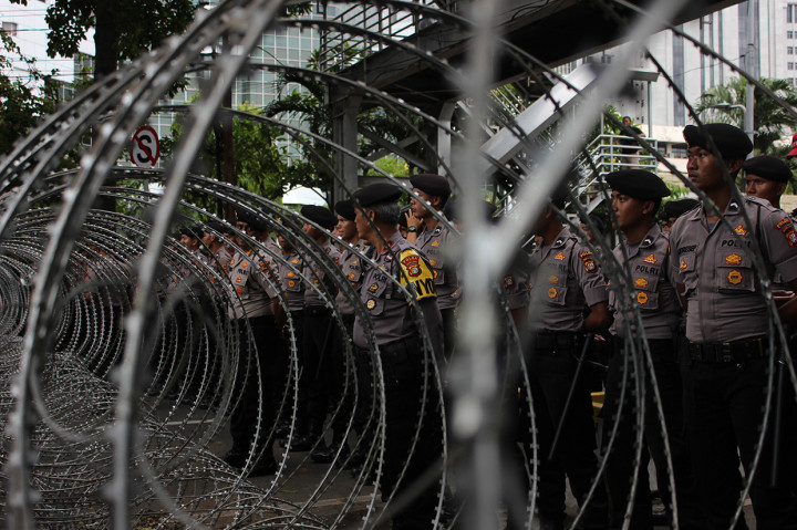 Personel kepolisian berjaga di belakang kawat berduri saat peringatan Hari Buruh Internasional di Jalan Medan Merdeka Barat, Jakarta Pusat. Jalan Medan Merdeka Barat ditutup kawat berduri yang membuat buruh dari berbagai serikat pekerja tidak dapat melakukan long march menuju kawasan depan Istana Merdeka. Antara Foto/Arindra Meodia