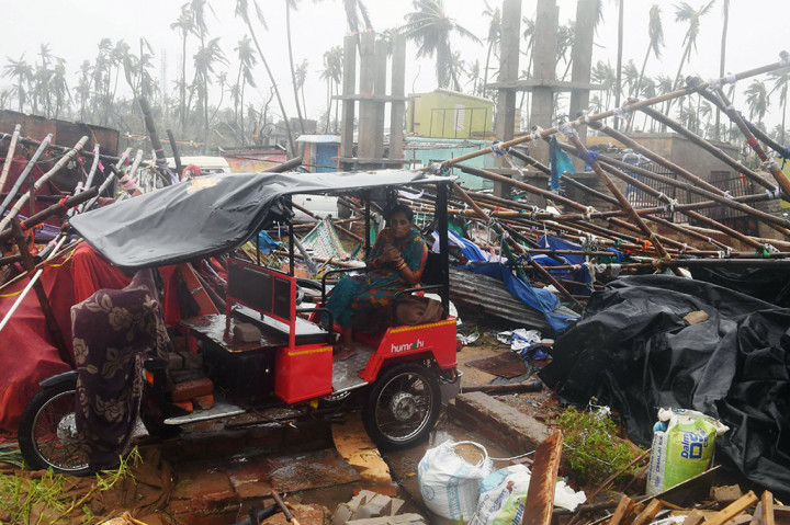 Seorang warga yang kedinginan duduk di atas becak listrik di dekat sebuah bangunan yang rusak diterjang topan Fani di Puri, Odisha.