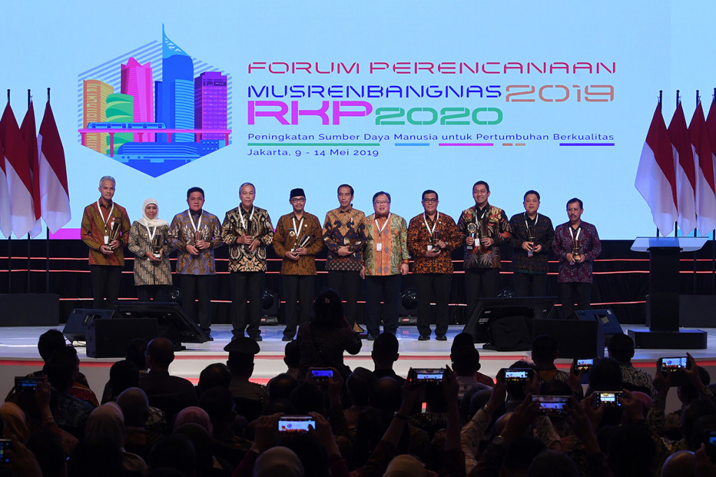 Presiden Joko WIdodo (tengah) didampingi Menteri Perencanaan Pembangunan Nasional/Kepala Bappenas Bambang Brodjonegoro (kelima kanan) berfoto dengan kepala daerah peraih penghargaan saat membuka acara Musyawarah Perencanaan Pembangunan Nasional (Musrenbangnas) 2019 di Jakarta.