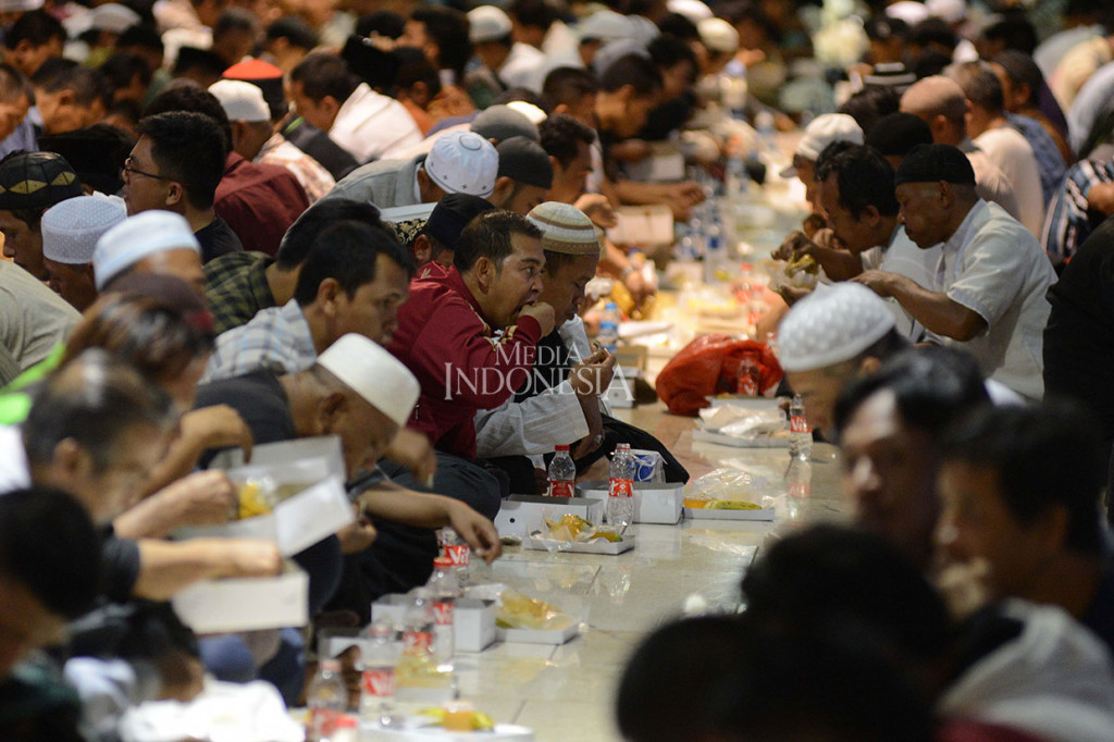 Saat waktu berbuka puasa tiba, ribuan warga yang duduk bersila saling berhadapan di lantai dua pelataran masjid menyantap makanan itu setelah berdoa.