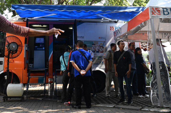 Warga antre menukarkan uang di mobil kas keliling bank BNI di Lapangan IRTI Monas, Jakarta.