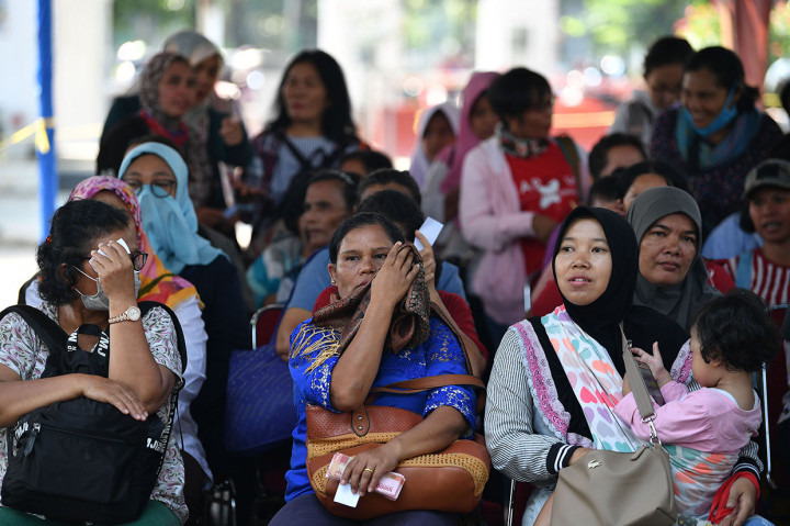 Warga mengantre untuk melakukan penukaran uang di mobil kas keliling bank di Lapangan IRTI Monas, Jakarta.