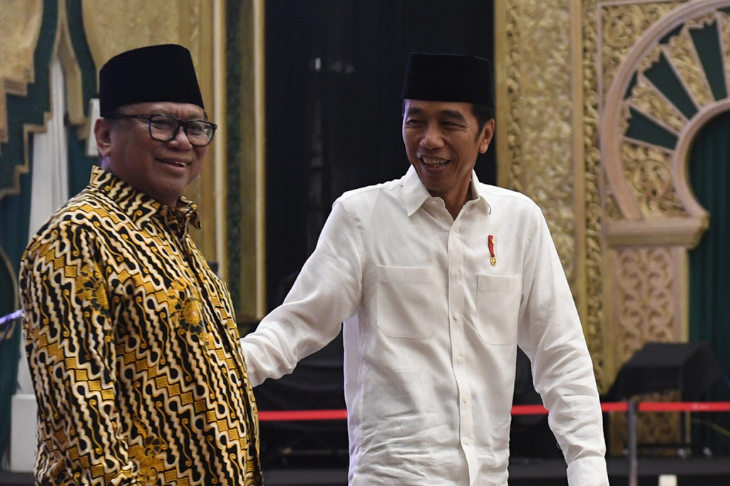 Jokowi tampak mengenakan kemeja koko warna putih dan peci warna hitam.