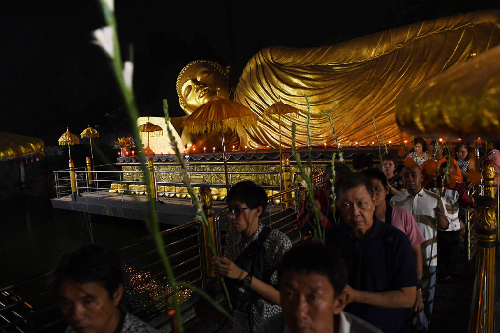 Umat Buddha mengelilingi patung Buddha Tidur saat perayaan Waisak 2563 BE di Maha Vihara Mojopahit Trowulan, Mojokerto, Jawa Timur.