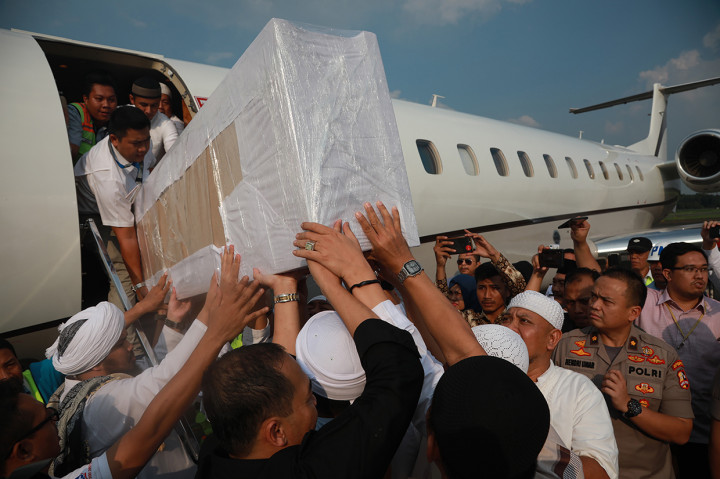 Jemaah membawa peti berisi jenazah Ustad Arifin Ilham yang baru tiba dari Penang, Malaysia di Bandara Halim Perdanakusuma, Jakarta Timur. 
