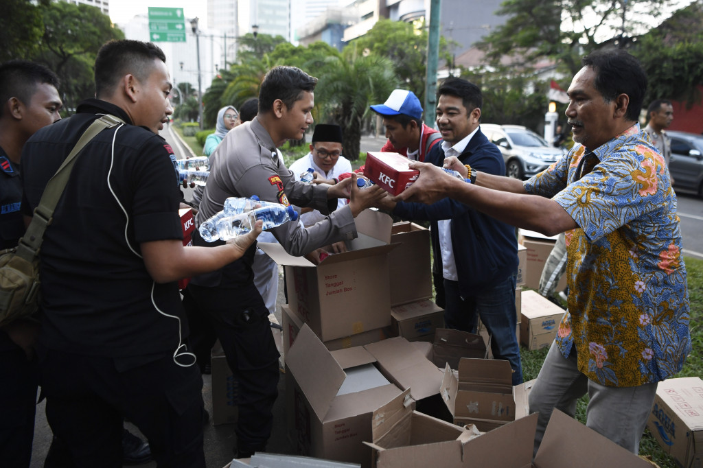 Koordinator Nasional Relawan Golkar Jokowi (Gojo) Rizal Mallarangeng (kanan) memberikan takjil kepada anggota Polri yang bertugas di Kantor KPU, Jakarta.