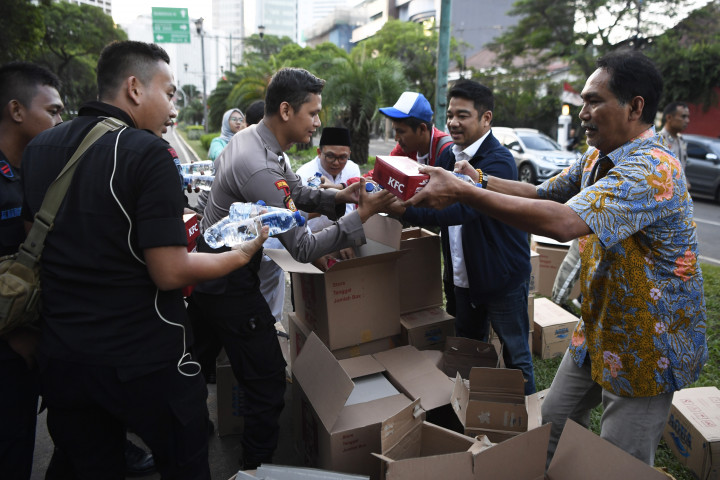 Koordinator Nasional Relawan Golkar Jokowi (Gojo) Rizal Mallarangeng (kanan) memberikan takjil kepada anggota Polri yang bertugas di Kantor KPU, Jakarta.