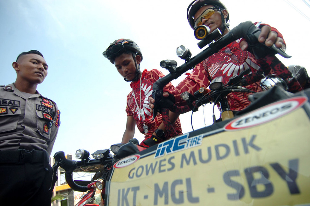 Goetheng (kanan) bersama anaknya Arfan (13) menggunakan sepeda beristirahat saat melintasi di jalur Pantura, Tegal, Jawa Tengah. Antara Foto/Oky Lukmansyah