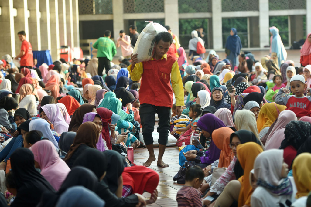 Sejumlah petugas membagikan beras zakat fitrah kepada sejumlah mustahik (warga penerima zakat) di Masjid Istiqlal, Jakarta.