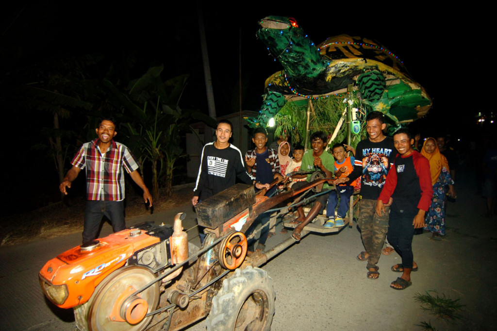 Sejumlah warga menggunakan traktor mengikuti pawai malam takbiran di Desa Harjasari, Kabupaten Tegal, Jawa Tengah. Pawai takbiran yang diikuti sekitar 40 traktor milik para petani setempat dengan dihias berbagai macam replika hewan dan tokoh film kartun raksasa tersebut untuk memeriahkan malam Lebaran 2019. ANTARA FOTO/Oky Lukmansyah