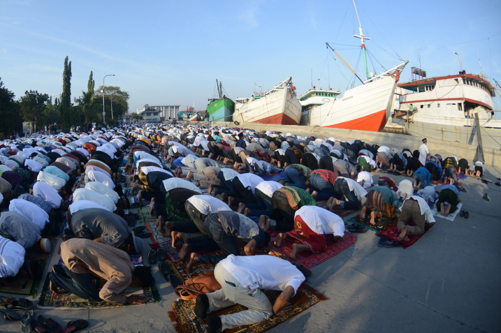 Ketika jamaah menjalani salat di dermaga, kapal-kapal nelayan yang ditambatkan di sana menjadi latar belakangnya.

