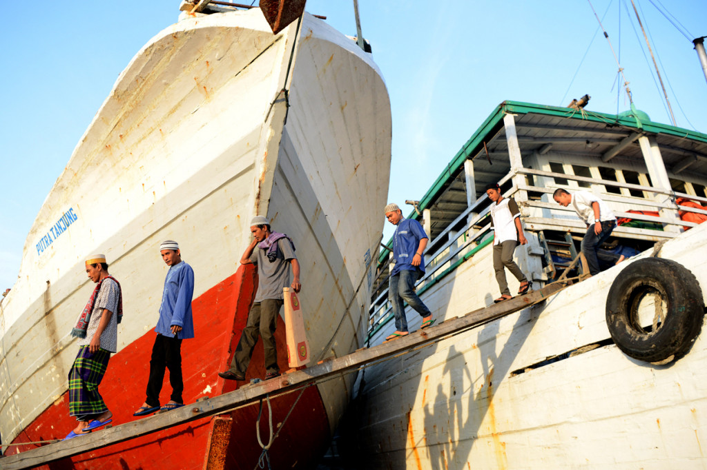 Sejumlah umat Islam meniti kayu pada kapal ke darat untuk melaksanakan shalat Idul Fitri 1 Syawal 1440 Hijriah di kawasan Pelabuhan Sunda Kelapa, Jakarta.
