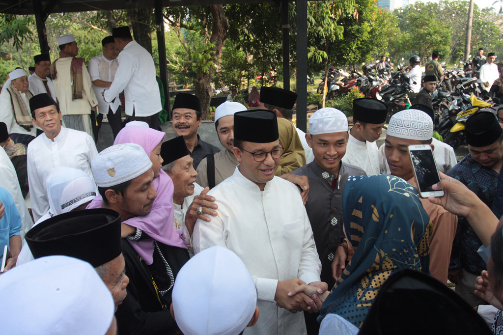 Gubernur DKI Jakarta Anies Baswedan (tengah) bersalaman dengan warga usai menghadiri kegiatan halalbihalal dan doa bersama saat perayaan Idul fitri hari kedua di Makam Wakaf Muslim, Lebak Bulus, Jakarta.