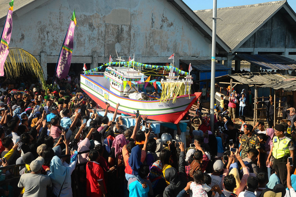 Warga mengangkat miniatur kapal yang berisi sesaji kepala kerbau, ingkung (ayam utuh), jajanan pasar, serta kupat dan lepat, sebelum dilarung di Pantai Kartini, Jepara, Rabu, 12 Juni 2019.