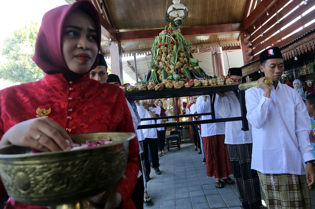Warga membawa gunungan ketupat coklat saat kitab ketupat berbahan olahan beras dan bubuk coklat  di kawasan wisata Kampung Coklat Blitar, Jawa Timur. Antara Foto/Irfan Anshori
