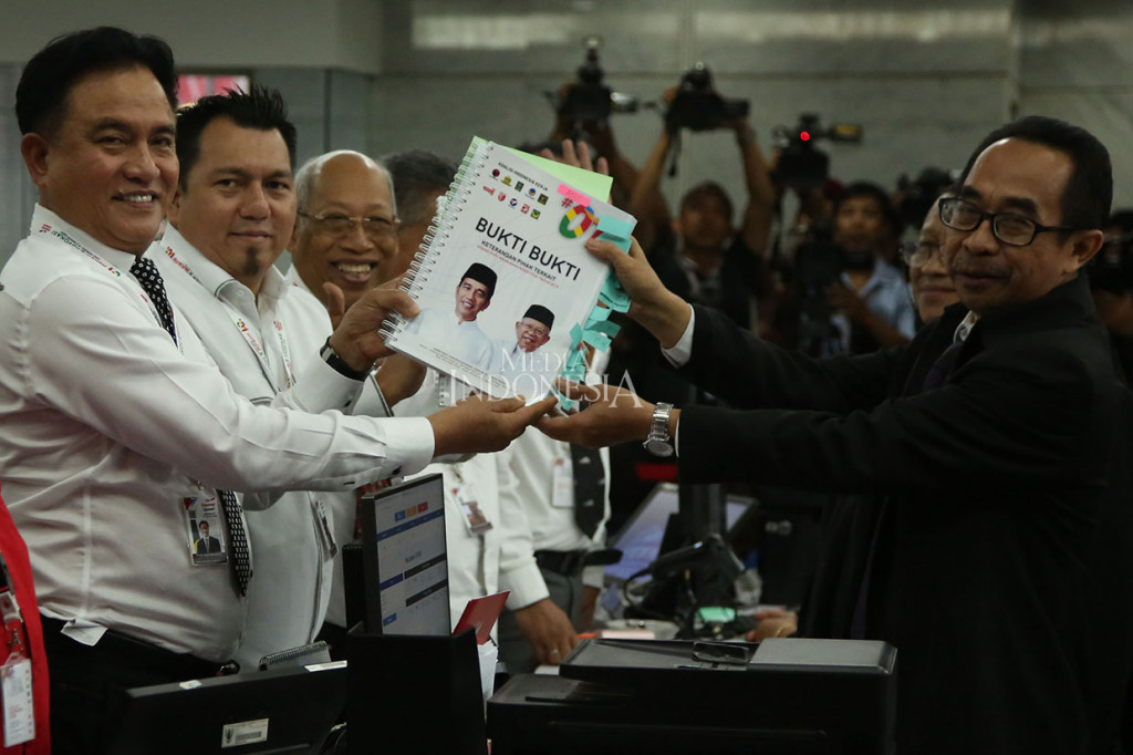 Ketua tim hukum Jokowi-Ma'ruf, Yusril Ihza Mahendra (kiri) bersama Direktur Hukum dan Advokasi TKN, Ade Irfan (dua kiri) serta tim menerima tanda bukti penyerahan berkas dan bukti-bukti jawaban/keterangan sebagai Pihak Terkait dari petugas di Mahkamah Konstitusi, Jakarta, Kamis, 13 Juni 2019. 