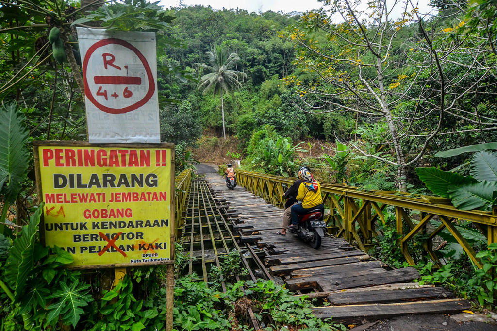 Pengendara motor melintasi Jembatan Bailey Gobang yang rusak di Kampung Gobang, Kota Tasikmalaya, Jawa Barat, Jumat, 14 Juni 2019.