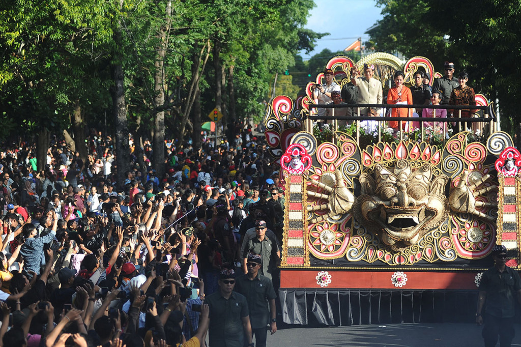 Saat berada di atas kendaraan tersebut, Jokowi, Iriana, dan sang cucu Jan Ethes tak henti melambaikan tangan kepada masyarakat Bali yang berdiri di sisi kanan-kiri Jalan Raya Puputan, Renon, sebagai jalan yang dilintasi pawai tersebut. Warga menyemut dan terlihat begitu antusias menyambut Presiden yang berdiri di atas kendaraan hias. Antara Foto/Fikri Yusuf