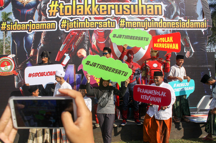 Warga berfoto bersama sambil mengangkat poster bertuliskan pesan damai saat kegiatan deklarasi masyarakat Jatim dan Surabaya tolak kerusuhan untuk Indonesia Damai dengan tagar #TolakKerusuhan di Alun alun Sidoarjo, Jawa Timur, Minggu, 16 Juni 2019. 