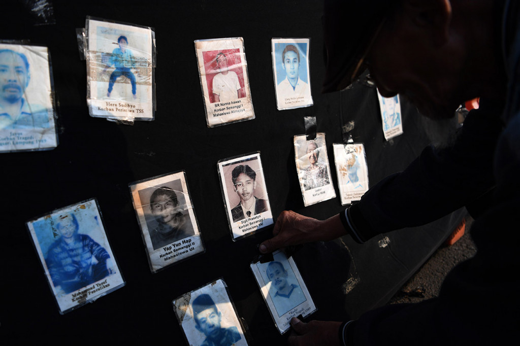 Seorang anggota Jaringan Solidaritas Korban untuk Keadilan menempel foto Korban pelanggaran HAM saat mengikuti aksi Kamisan ke-589 di depan Istana Merdeka, Jakarta.