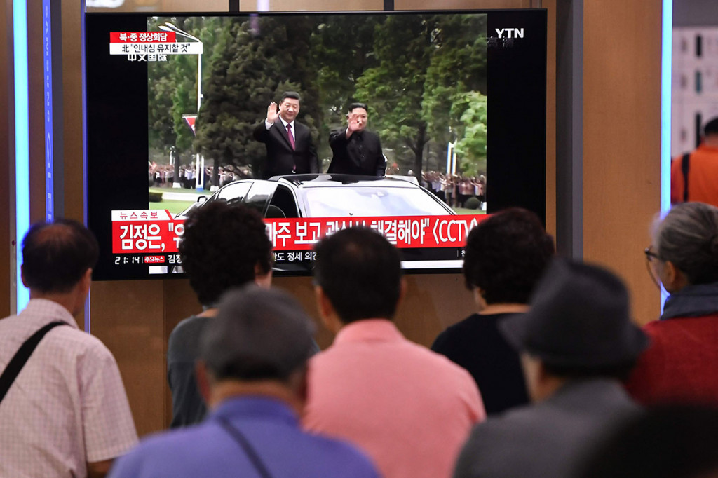 Warga menyaksikan berita Presiden Tiongkok Xi Jinping (kiri) disambut Pemimpin Korut Kim Jong-un, di televisi sebuah stasiun kereta api di Seoul, Korsel.