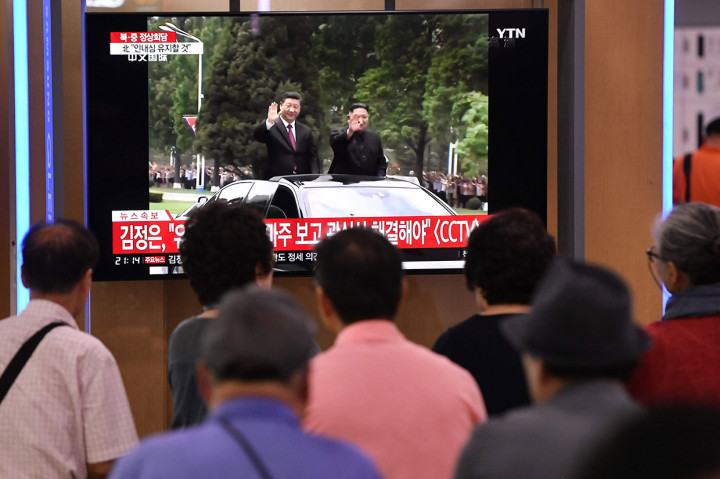 Warga menyaksikan berita Presiden Tiongkok Xi Jinping (kiri) disambut Pemimpin Korut Kim Jong-un, di televisi sebuah stasiun kereta api di Seoul, Korsel.