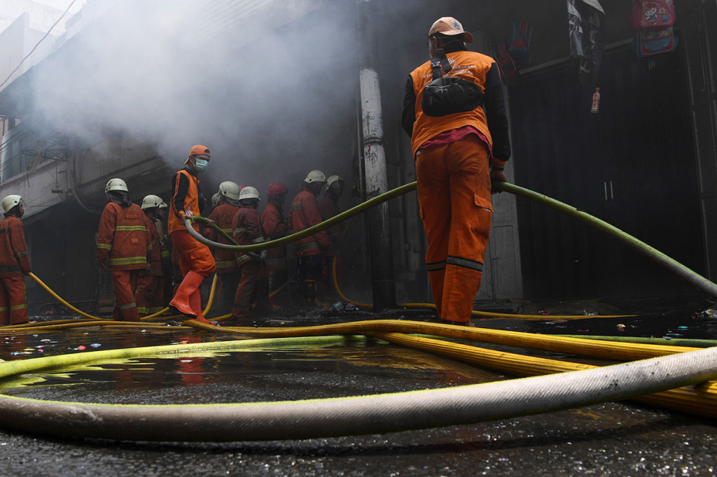 Petugas pemadam kebakaran berusaha memadamkan api yang membakar gudang kembang api di Pasar Pagi Asemka, Jakarta, Jumat, 21 Juni 2019.