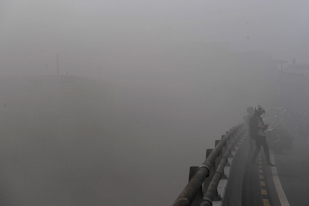 Warga berada di fly over yang diselimuti asap akibat kebakaran gudang penyimpanan kembang api. Gudang penyimpanan kembang api terletak di bawah fly over, Pasar Pagi Asemka.