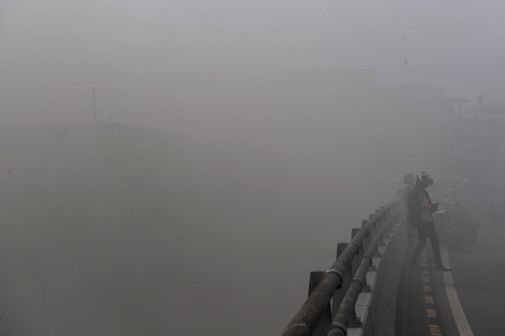 Warga berada di fly over yang diselimuti asap akibat kebakaran gudang penyimpanan kembang api. Gudang penyimpanan kembang api terletak di bawah fly over, Pasar Pagi Asemka.